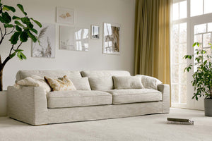 Beige textured 4 seater sofa with cushions and picture wall